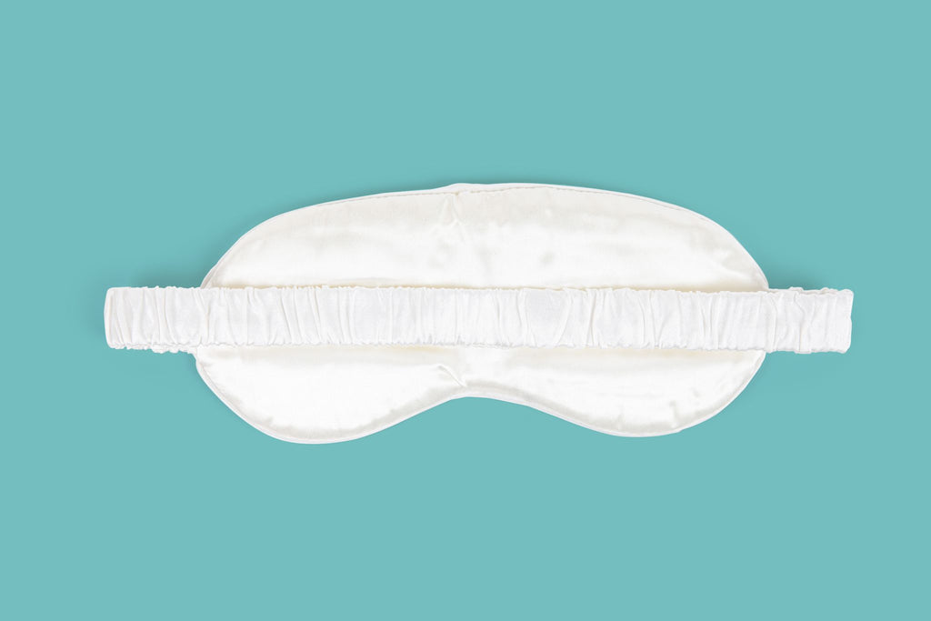 Ameline Ava Pearly White lustrious 100% Mulberry Silk Eye Mask, against blue background