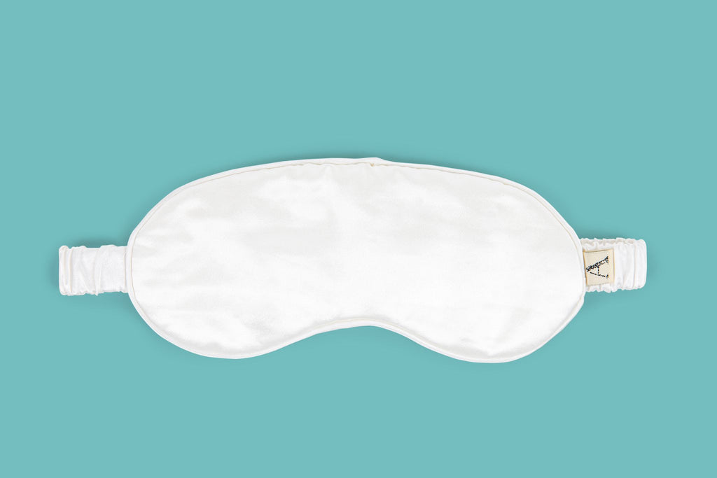 Ameline Ava Pearly White lustrious 100% Mulberry Silk Eye Mask, against blue background