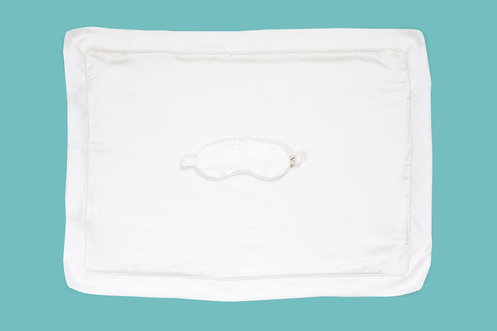 Ameline Ava Pearly White lustrious 100% Mulberry Silk Oxford Pillowcase and Eye Mask Gift Set, against blue background